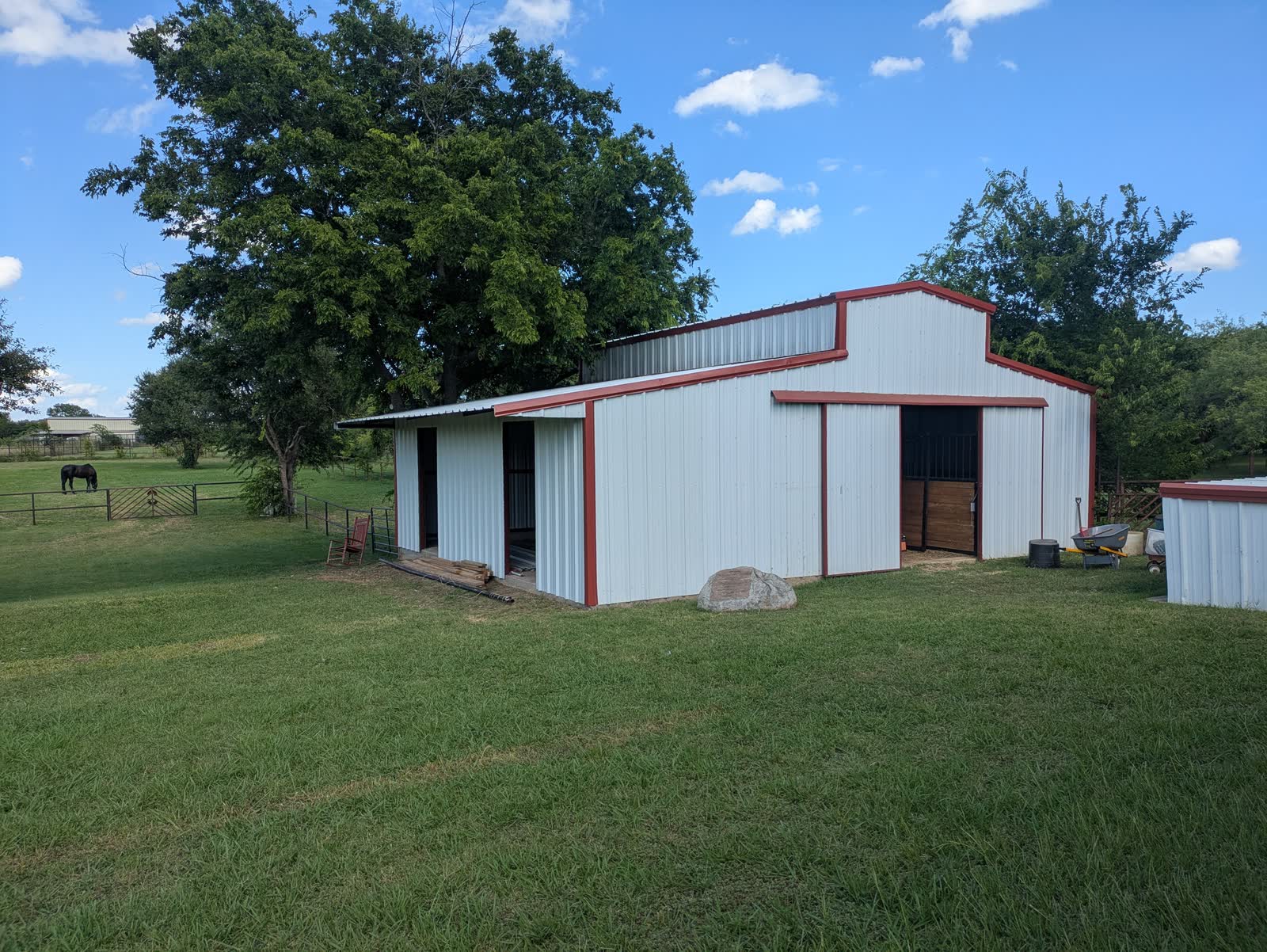 The barn from outside: a white steel building with red trim, in a pasture
