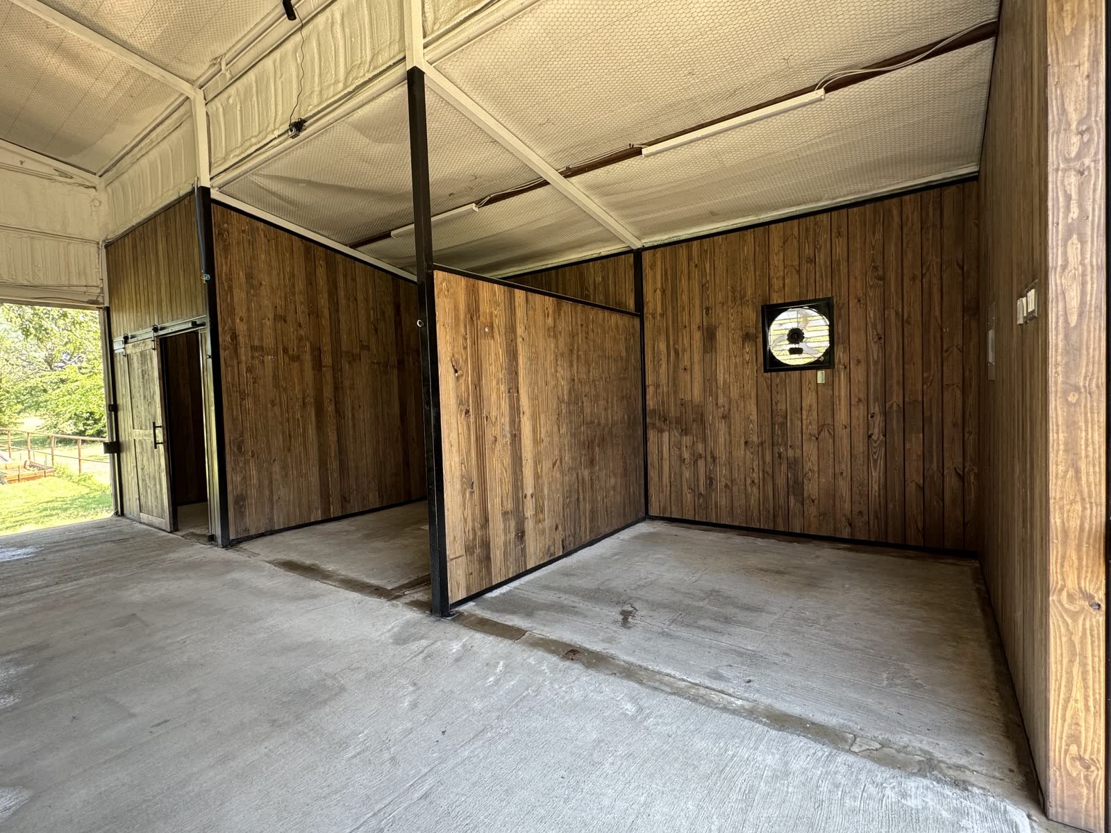 Wood-lined feed storage room with an exhaust fan, and the grooming stall on the left