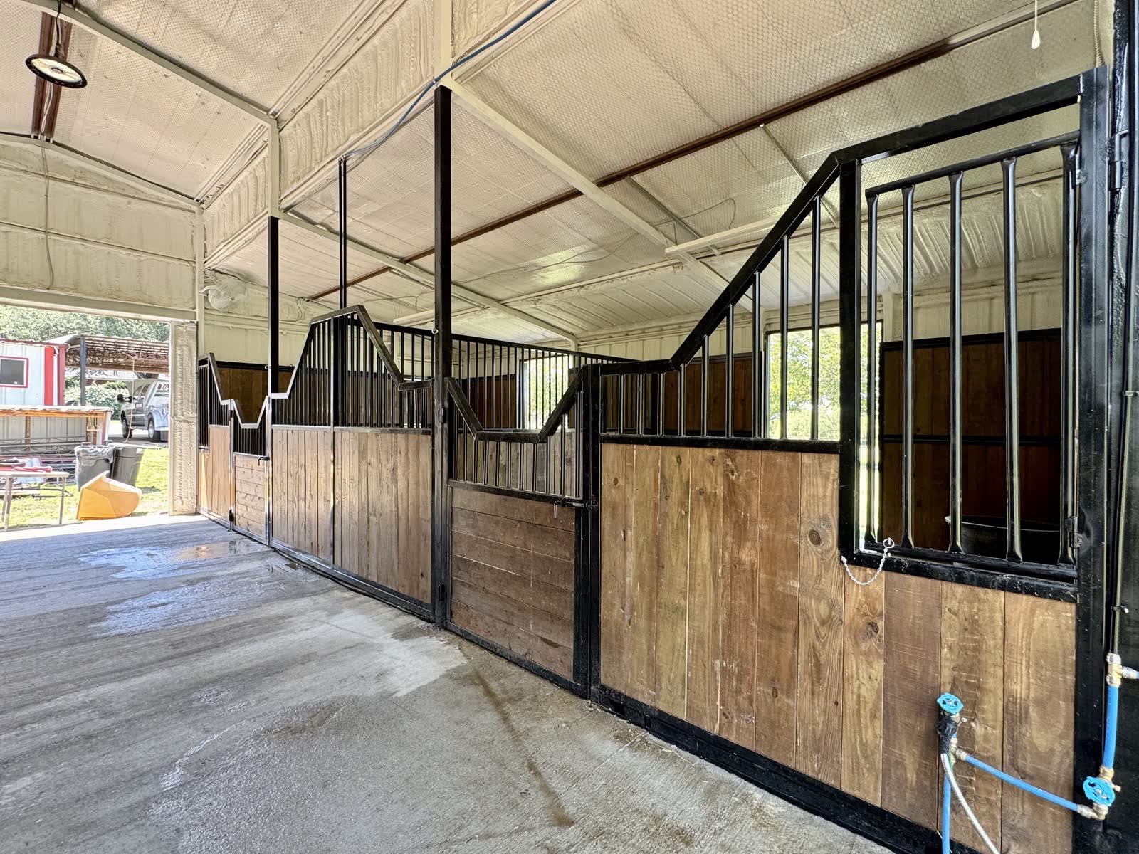 Finished aisle along the new stalls, with water lines and valves run along the stall wall
