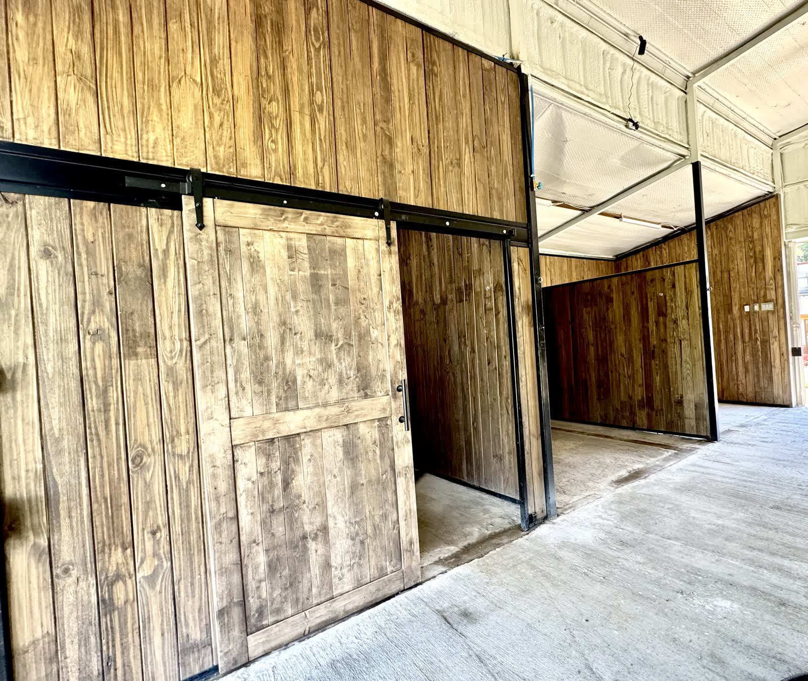 Front of the tack room: a full-height wood sliding door on a black steel track