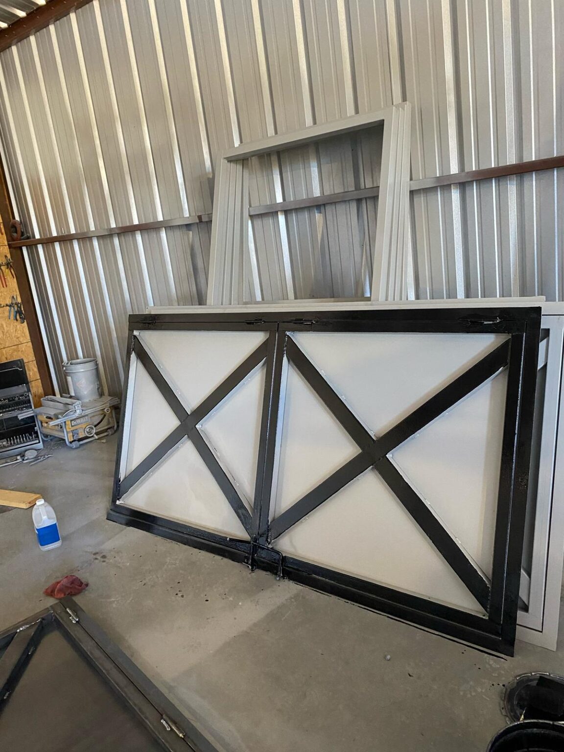 Custom steel Dutch barn door with cross-buck panels, laid on its side in the TexTuff shop