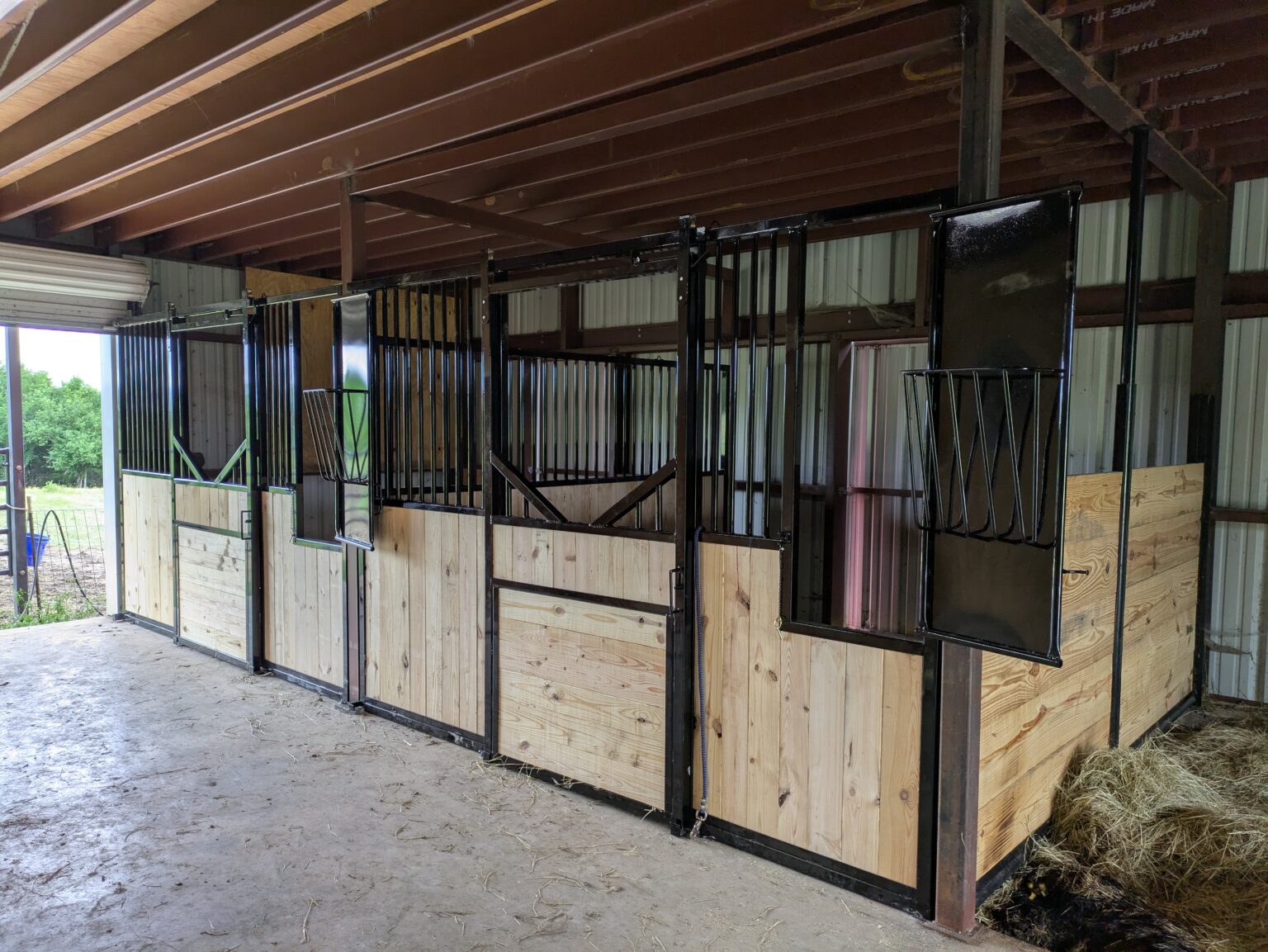 Three stall fronts with swing-out hay racks and an open barn door