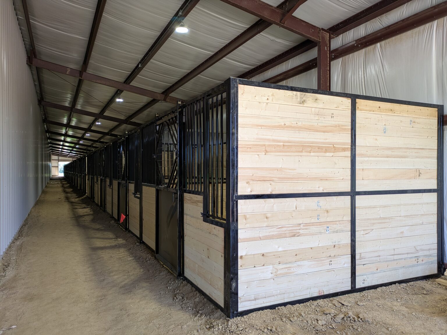 Row of 20 custom TexTuff stalls along the side of the riding arena at Flying F Arena, Harrisburg, Arkansas