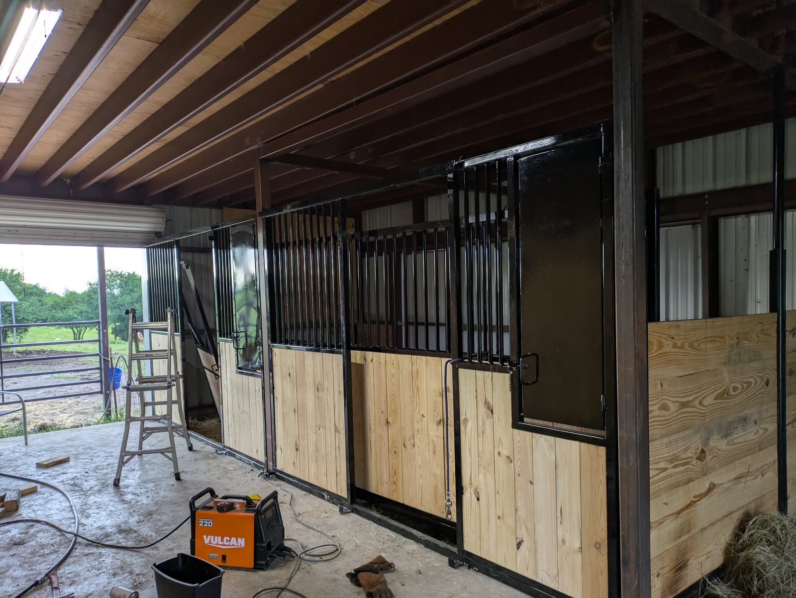Install in progress: sliding door and solid black steel feed door hung on the new fronts, with a welder on the floor