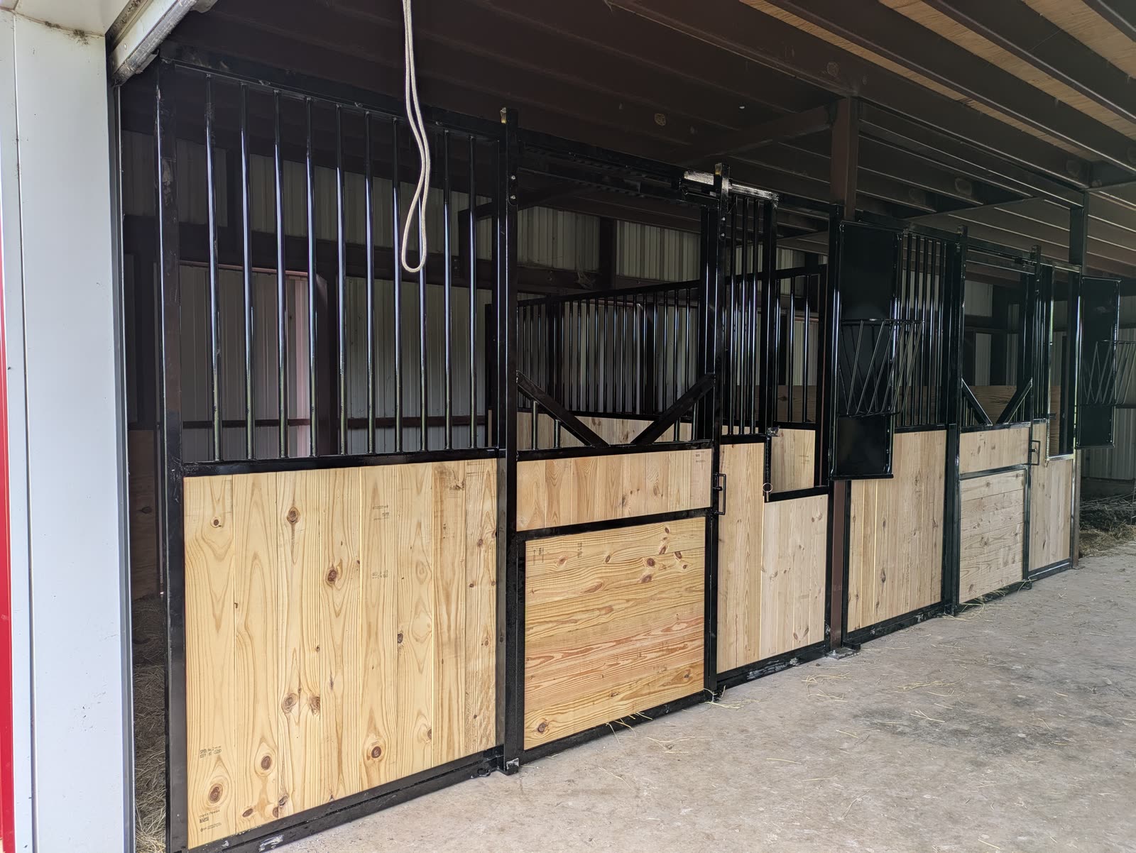 Close-up of the finished fronts: vertical steel bars over pine boards, sliding V-yoke doors, and feed doors